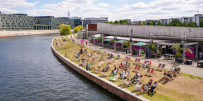 Bar Capital Beach Blick auf die am Spreeufer gelegene Bar Capital Beach mit Liegewiese und Gebäude.